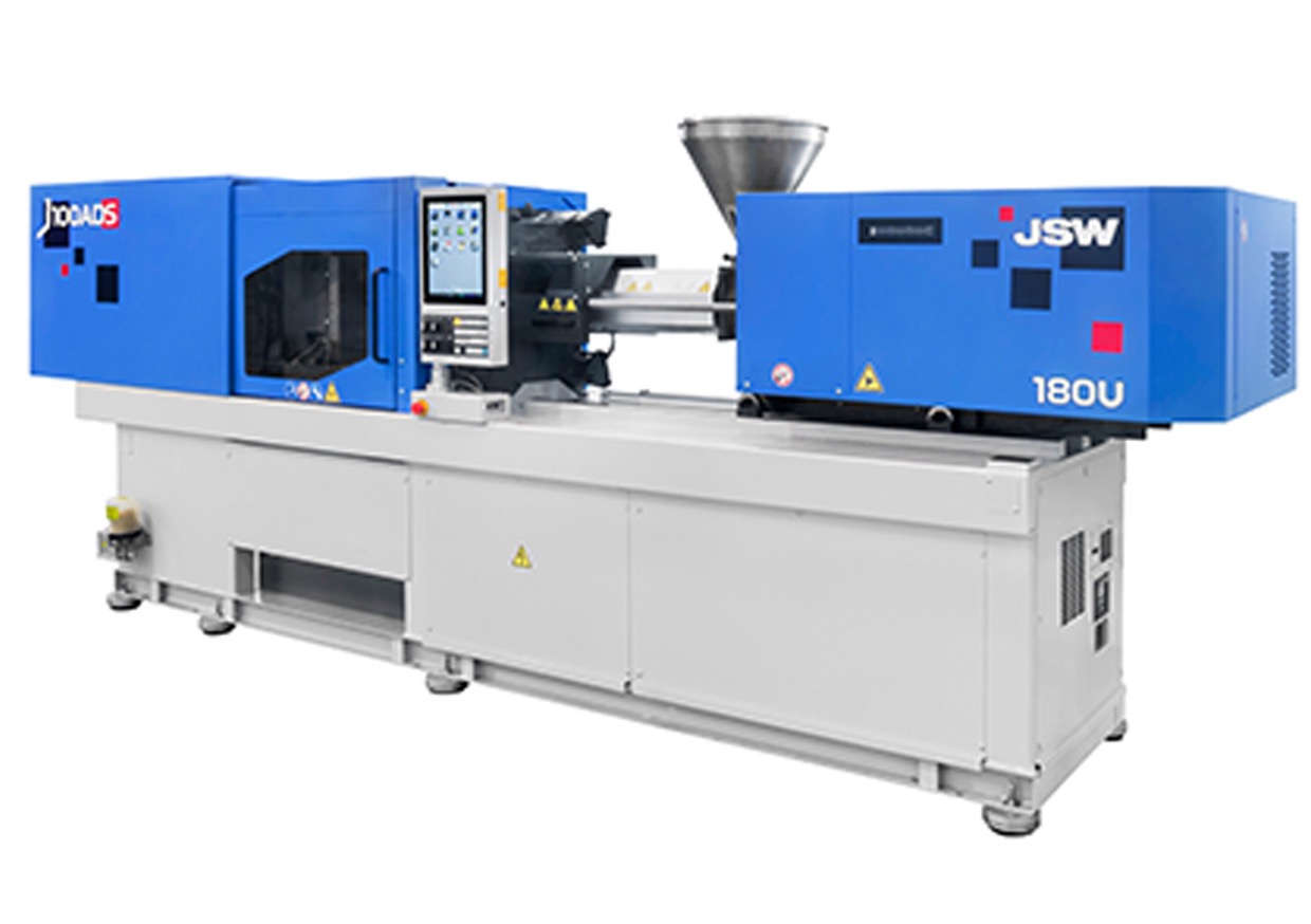 A blue and white injection molding machine labeled "JSW 180U." The machine includes controls on a touch panel display and a hopper for material feed at the top. It is set on a white base, with safety and caution signs visible on the machine’s body.