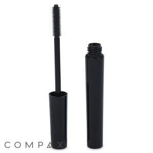 A black mascara tube standing upright with the cap removed and the mascara wand exposed, showing the bristles. The cap is leaning against the tube. The word "COMPAX" is written in the bottom left corner.