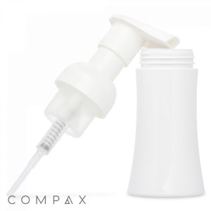 A 100 mL PET Foamer Bottle is shown against a plain white background. The white plastic pump dispenser is slightly angled, with the dispensing nozzle pointing downwards towards the white cylindrical bottle. The brand name "COMPAX" is displayed in light gray text at the bottom-left corner.