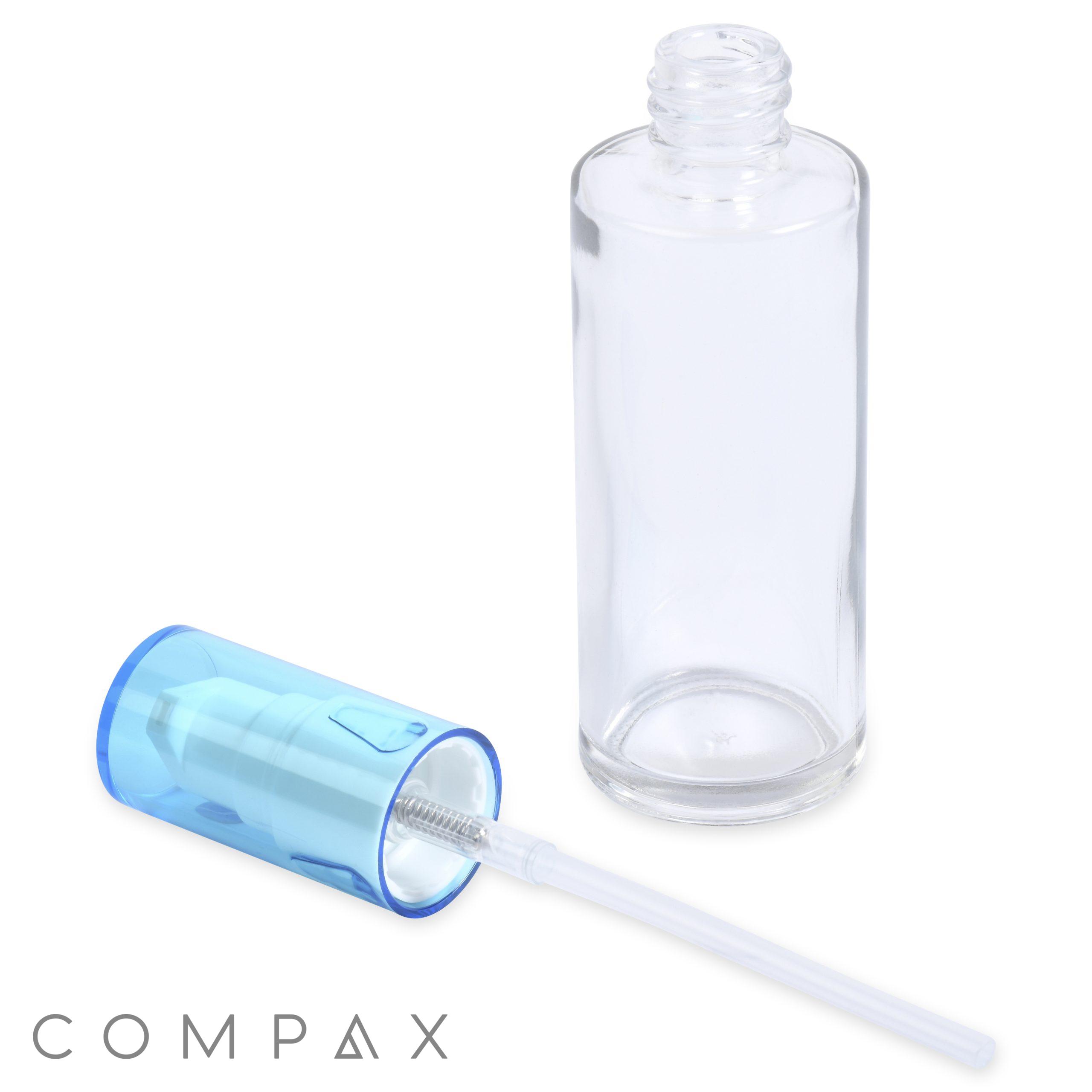 A 50mL glass cylinder round bottle with its blue pump dispenser removed and placed next to it. The pump has a long transparent tube attached. The brand name "COMPAX" is visible in the bottom-left corner.