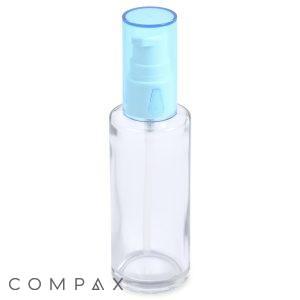 A 50mL glass cylinder round bottle with a transparent body, a light blue pump, and a clear cap, designed for dispensing liquids. The word "Compax" is written in gray text at the bottom left corner. The bottle is empty and stands upright against a plain white background.