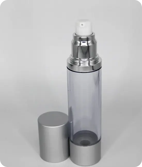 A clear airless pump bottle with a silver bottom and pump. The silver cap is removed and placed beside the bottle.